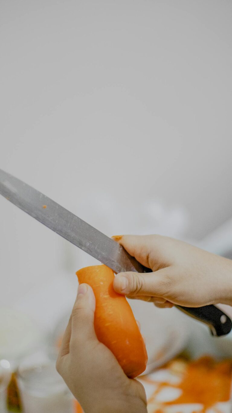 Crop cook cutting carrot in kitchen