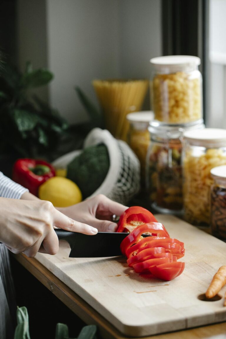 Faceless woman chopping bell pepper during lunch preparation in kitchen